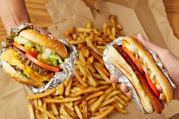 2-people-holding-burgers-and-chips