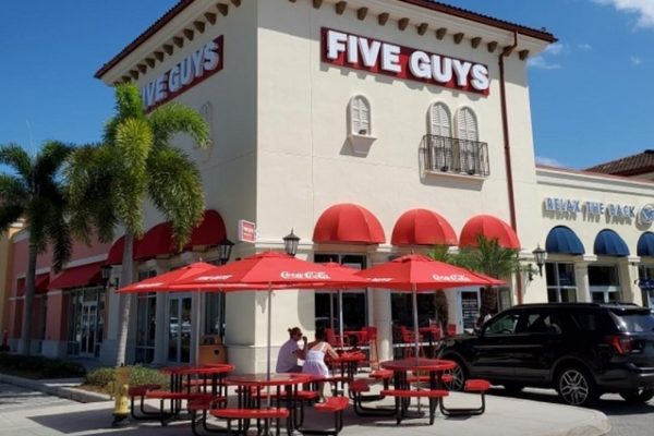 five-guys-sign-outside-building-palm-trees-red-chairs-and-tables