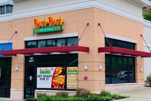 peri-peri-orginial-red-and-yellow-sign-on-brick-building-flowerbed