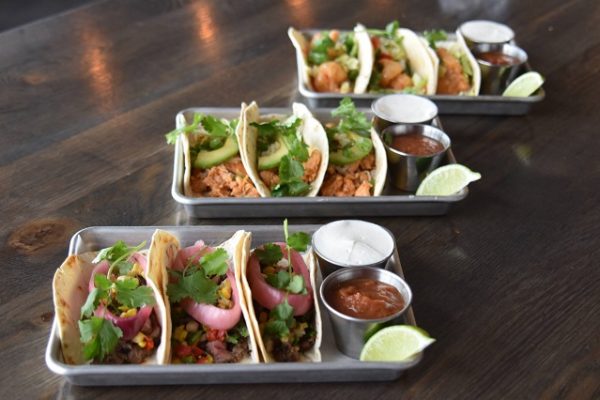 plates-of-tacos-salsa-coriander-on-wooden-table