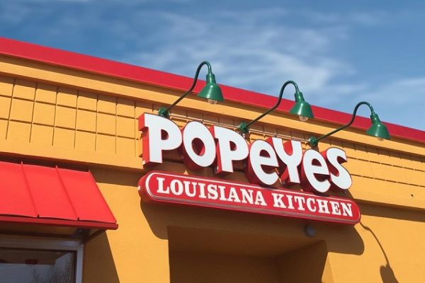 red-popeyes-sign-outside-building-blue-skies