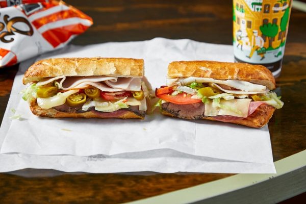 sandwich-cut-in-two-on-white-paper-and-wooden-table
