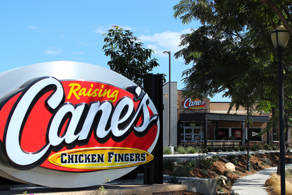 yellow-and-red-raising-canes-sign-with-building-in-the-backgorund