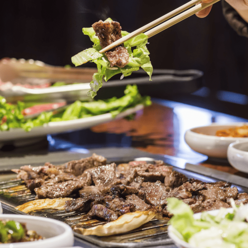 Korean beef strip with lettuce held with chopsticks at KBBQ Rappaport tenant
