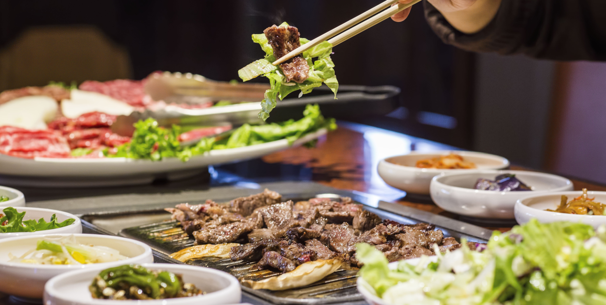 Korean beef strip with lettuce held with chopsticks at KBBQ Rappaport tenant