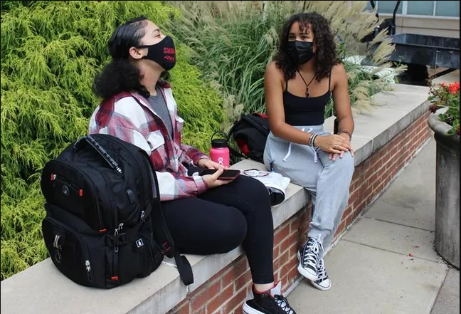 Spelman College first-year students Bianca Moore and Corinne Adams lounging outside one of the facility's buildings. Adams is a studio art major, while Moore is majoring in psychology.