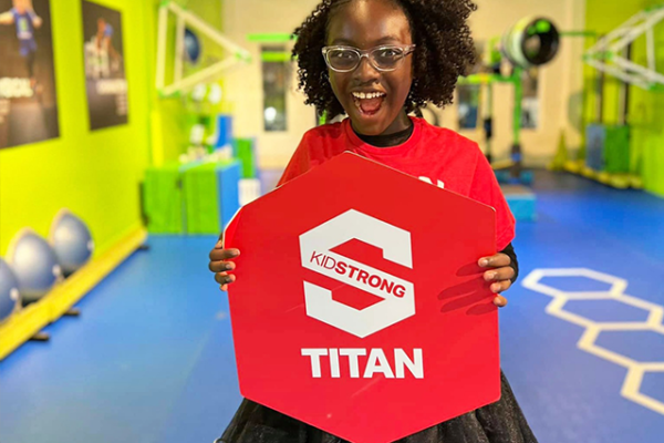 A girl holding a KidStrong Titan sign