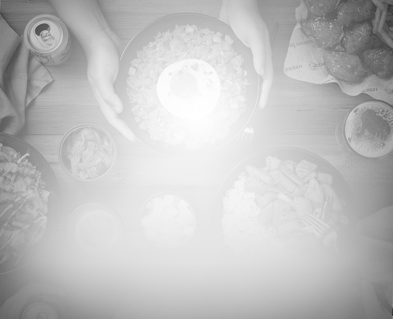 a spread of food in bowls in black and white the center bowl has hands around it as if passing it to someone