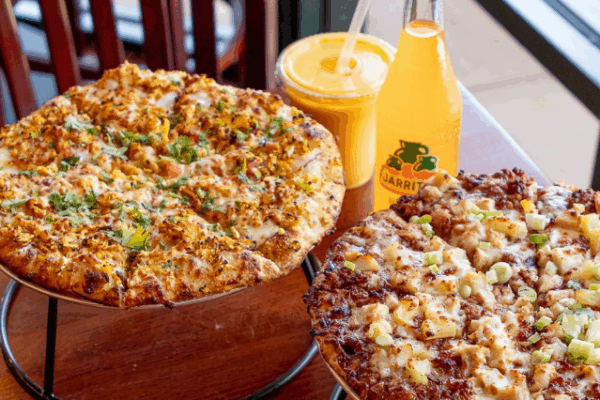 curry pizza house_2 two pizzas on pizza tier with a mango lassi and a jaritos