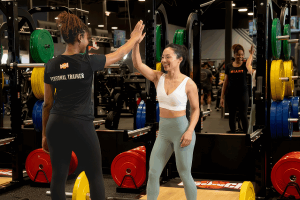 crunch fitness_1 woman high-fiving her personal trainer in the weigh lifting space